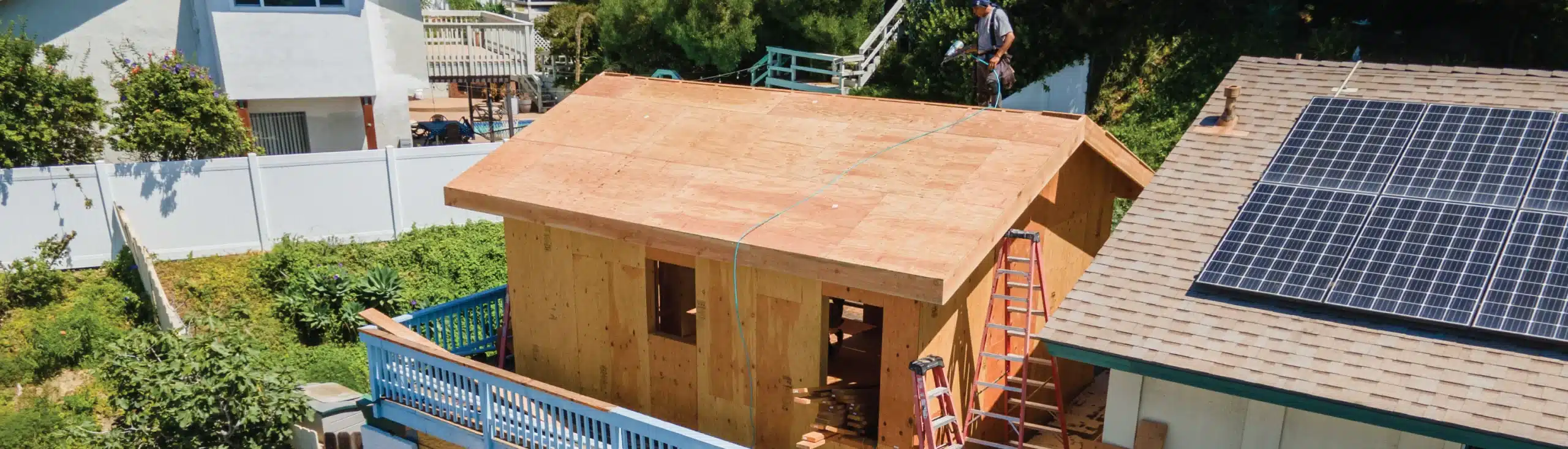 Construction of a detached ADU in progress, featuring wooden framing and roofing in a residential backyard. Highlights the early stages to build an ADU, emphasizing the craftsmanship and structural planning involved in expanding living spaces.