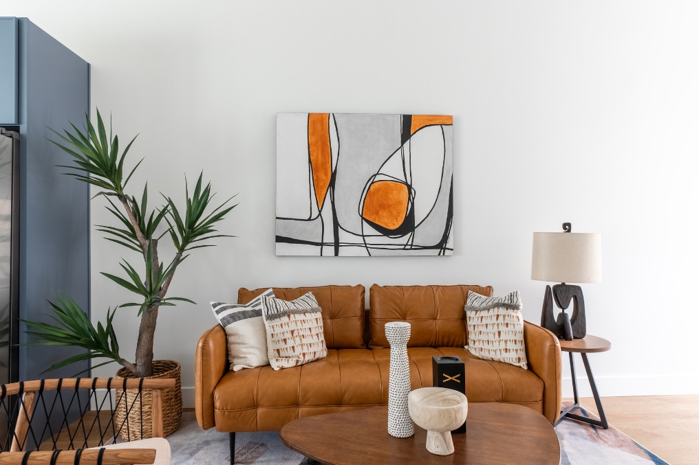 Inviting living room with contemporary artwork, leather sofa, and decorative accents in Pacific Beach detached ADU.