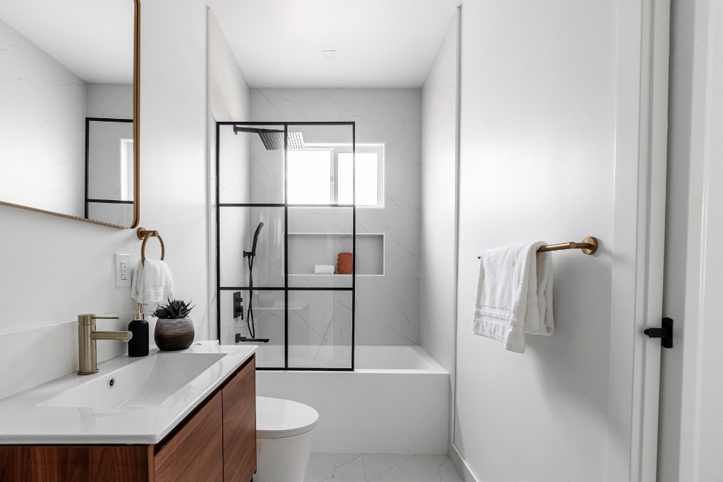 Contemporary bathroom design featuring black-framed glass shower enclosure and modern fixtures in Pacific Beach ADU.