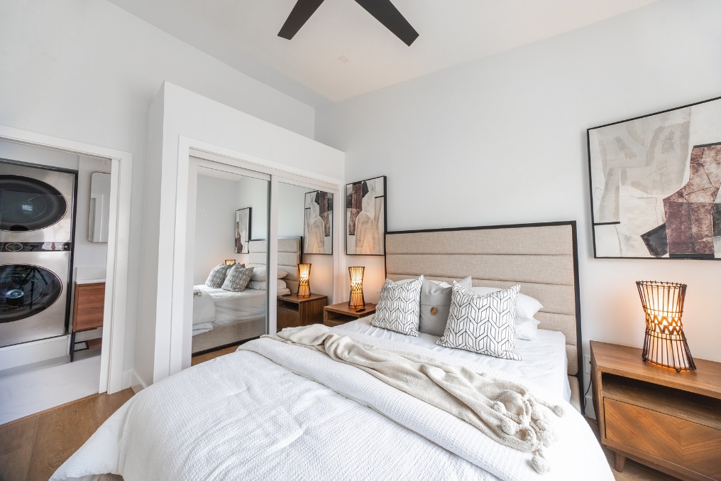Stylish Pacific Beach ADU bedroom featuring mirrored closets, modern decor, and convenient laundry access.