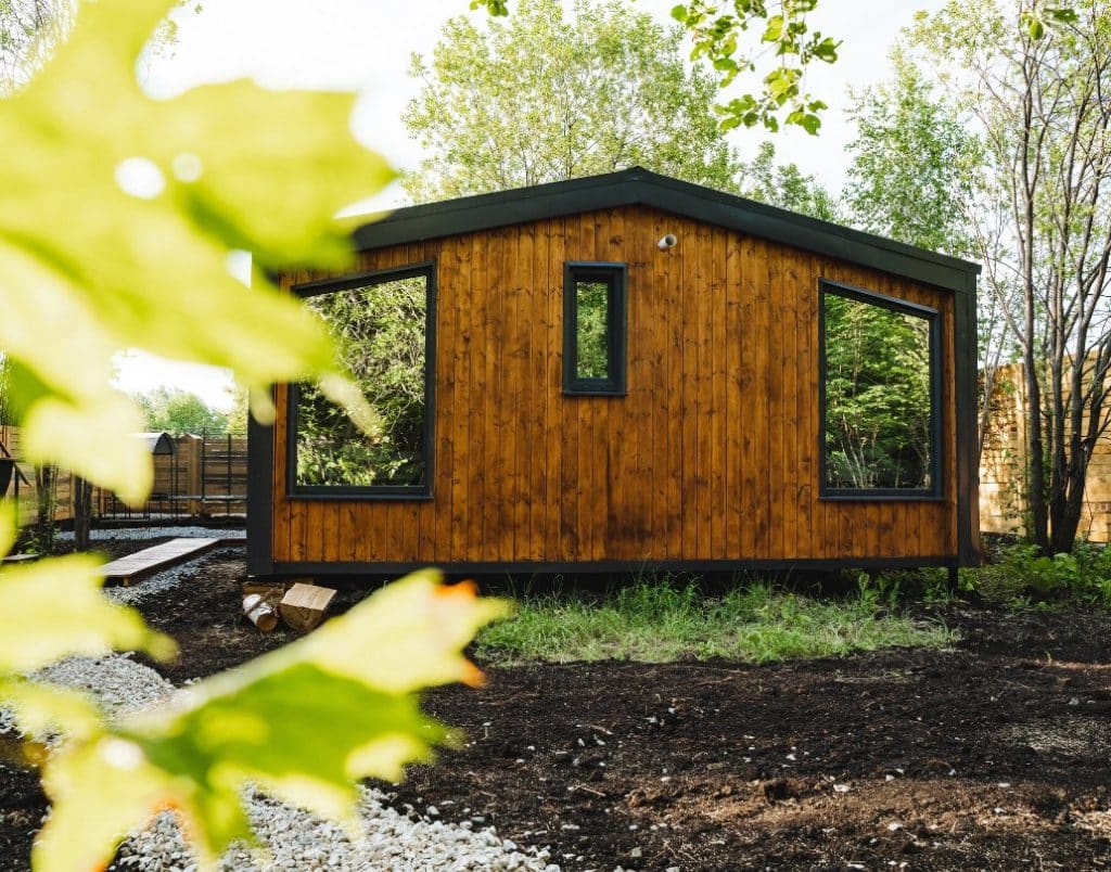 A stylish prefab modular ADU with wooden siding and large windows.