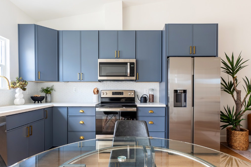 Sleek kitchen with stylish blue cabinetry, stainless steel appliances, and gold hardware in Pacific Beach detached ADU.