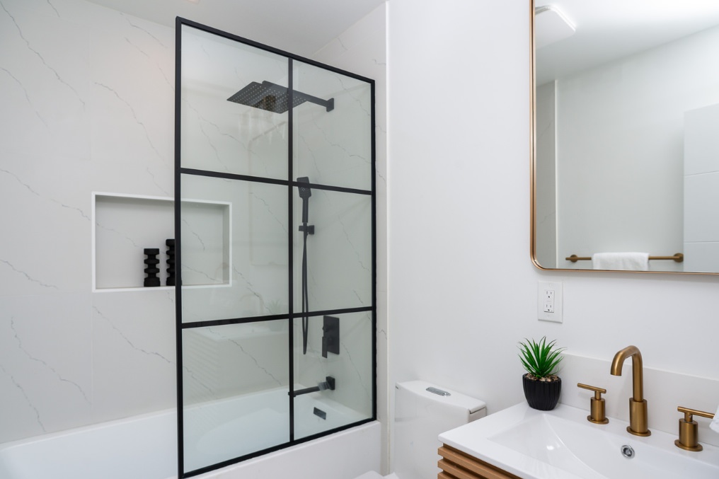 Modern bathroom with stylish black-framed shower and gold fixtures in Clairemont ADU