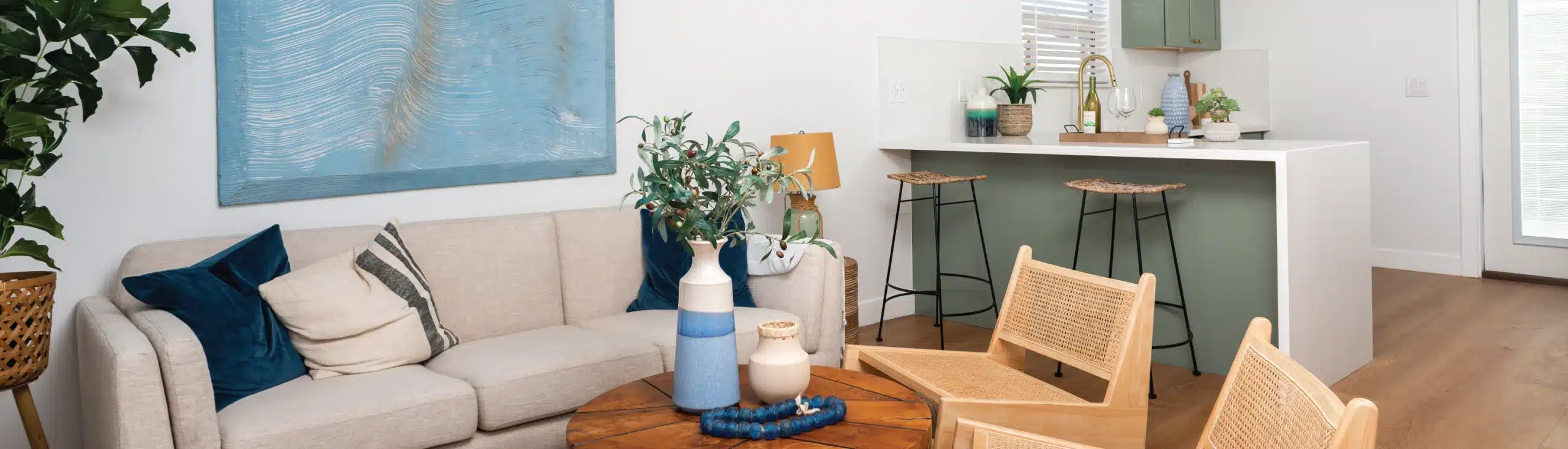 Cozy and stylish ADU living area with a neutral-toned sofa, modern seating, and a kitchen bar setup in the background. Showcases an efficient, inviting design that maximizes comfort in a small space, ideal for those considering ADU cost-effective living solutions without sacrificing style.