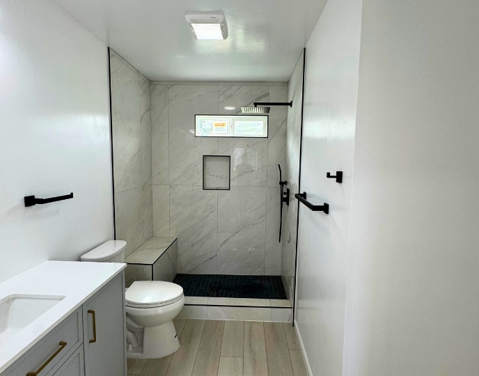 Modern bathroom in an ADU, featuring a spacious shower, sleek fixtures, and a minimalist design. Illustrates how an ADU can be fully equipped with a bathroom, addressing the question of whether a pool house or ADU can include essential amenities like a kitchen or bathroom for independent living.