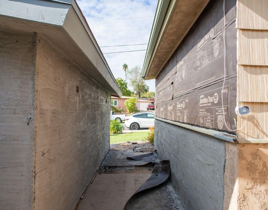 Narrow outdoor passageway between two structures under construction, showing foundational and wall preparations. Highlights the construction and space requirements for pool houses and ADUs, emphasizing the need for strategic planning and appropriate spacing to ensure both functional design and compliance with local building codes.