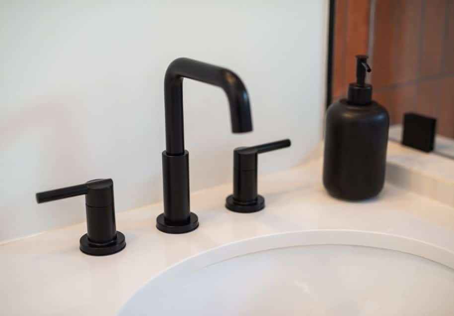 Modern black faucet and soap dispenser on a sleek white sink surface, showcasing premium build quality and features.