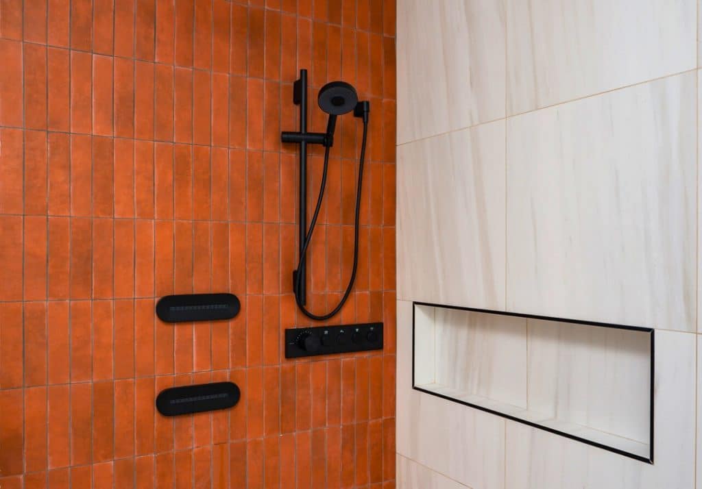 Accent wall with bold tile color adding vibrancy to a sleek ADU shower space