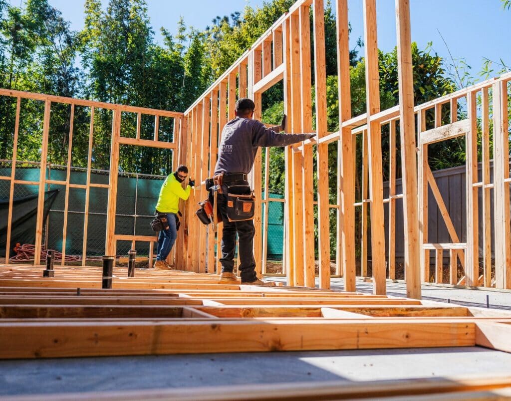 Two builders framing an ADU structure, illustrating progress under California SB13 incentives.