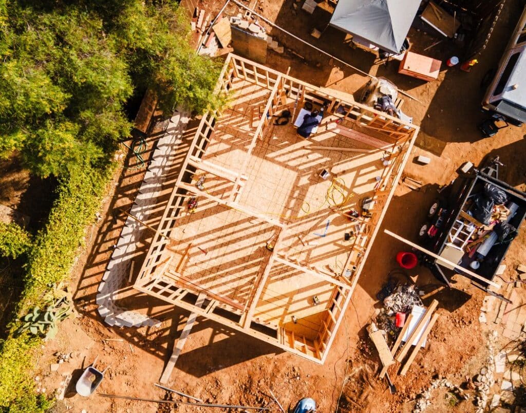 A bird’s eye view of an ADU construction site with visible foundations and framing work.