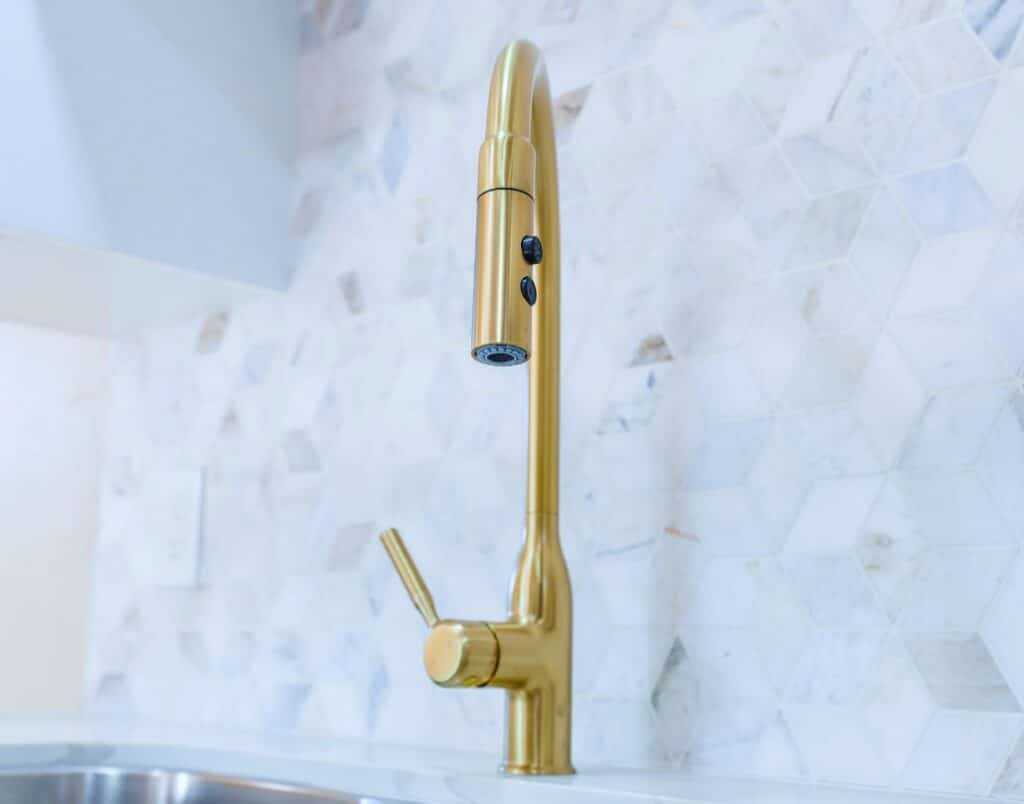 A sleek gold faucet installed in a modern ADU kitchen.