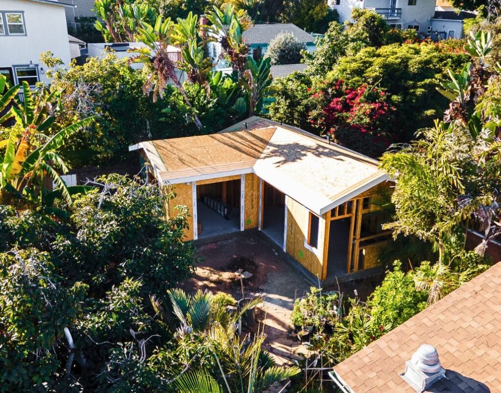 An aerial view of an ADU nestled among trees in a suburban backyard.