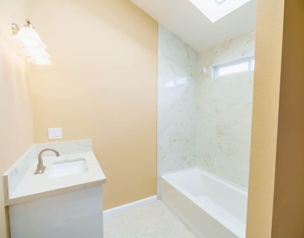 A modern bathroom with marble-like tiling and a skylight.