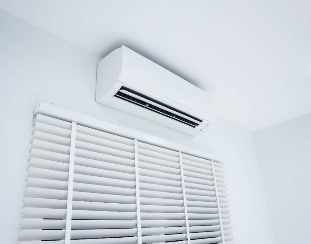 A sleek white air conditioning unit paired with blinds for optimizing natural light and ventilation.