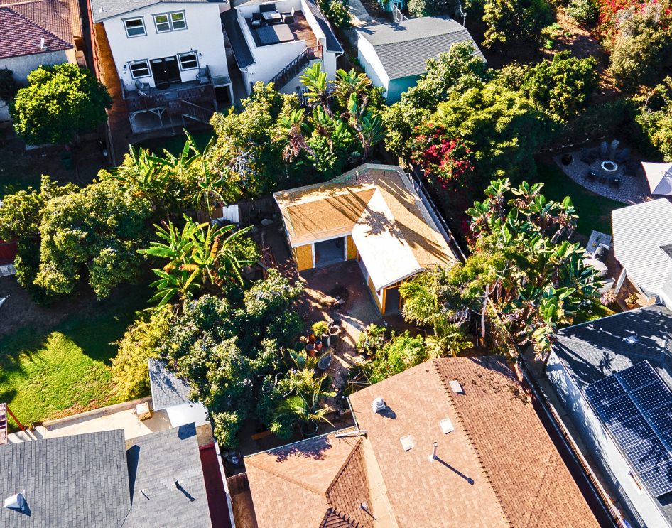  Overhead view of a custom ADU construction site surrounded by lush greenery, mid-way through the building process.