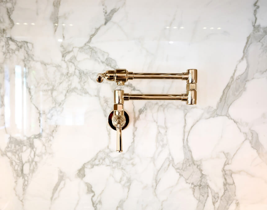 Water & Sewer Capacity Fees – gold pot filler faucet on marble backsplash in an ADU kitchen.