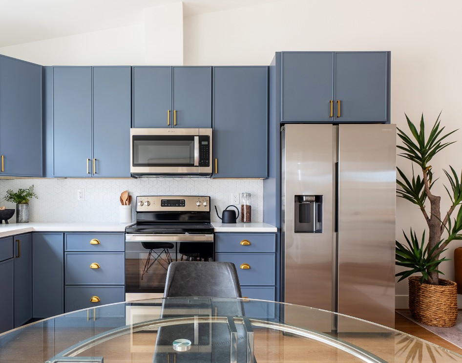 Stylish custom ADU kitchen with blue cabinetry, stainless steel appliances, and a modern dining area.