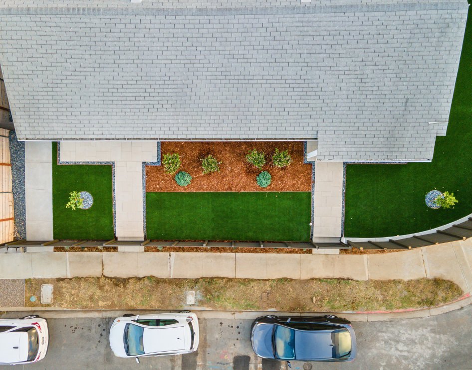 Aerial view of a completed ADU with a landscaped yard and paved walkway.