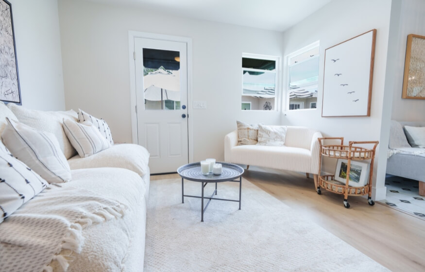 Interior view of a 400 sq ft ADU living room with soft neutral tones, a white couch, and modern accent chairs—showcasing designer tips for maximizing small-space comfort and style.