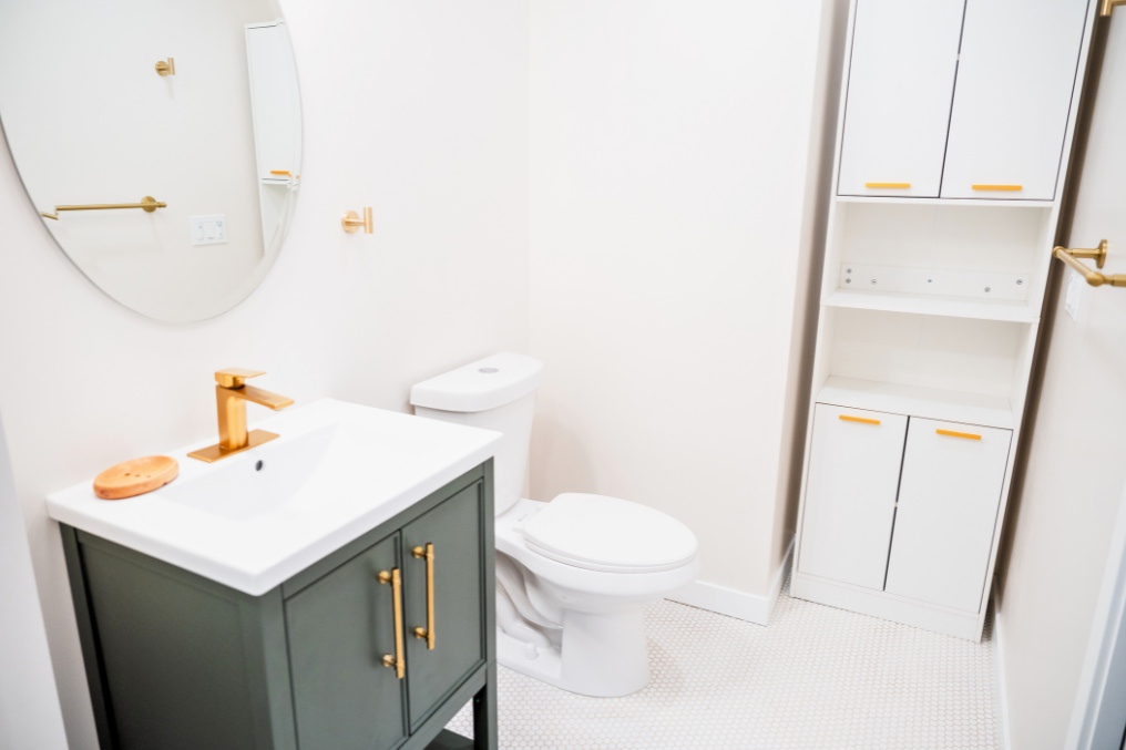 Contemporary bathroom featuring stylish vanity, white cabinetry, and round mirror in studio ADU.