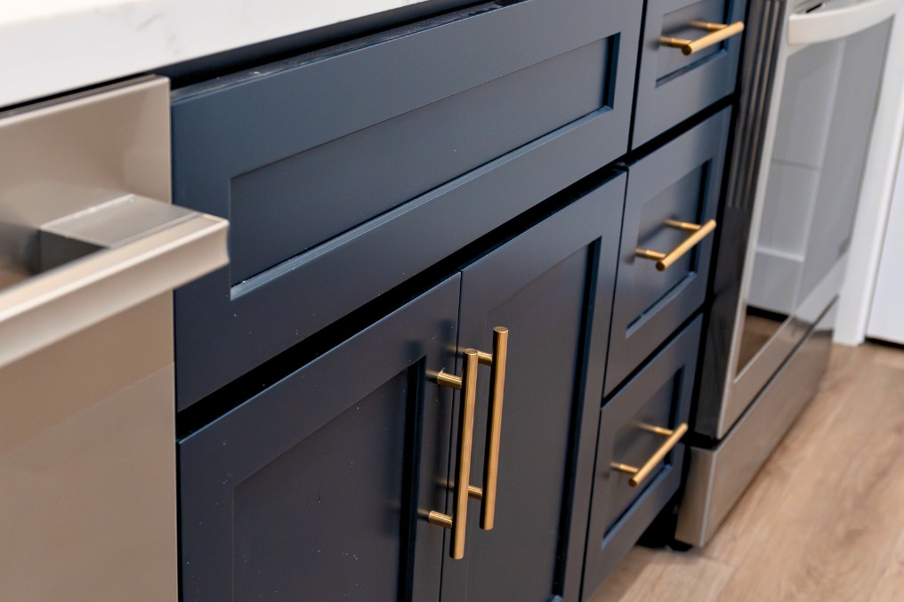 Detailed view of kitchen cabinetry in dark blue with modern gold hardware accents in contemporary ADU.