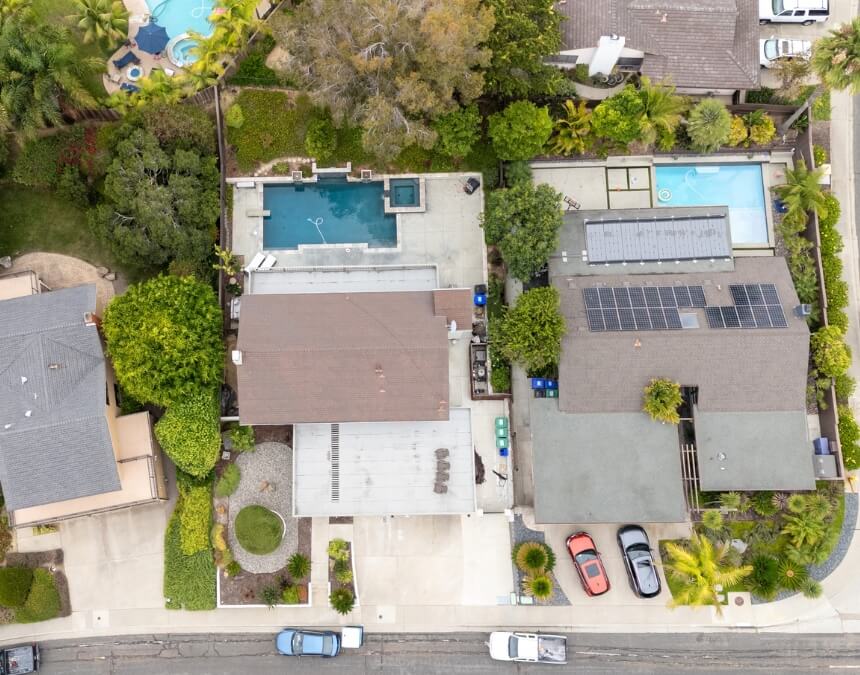 Aerial view of a San Diego home with solar panels on the main roof and visible ongoing construction of a secondary unit beside a pool.
