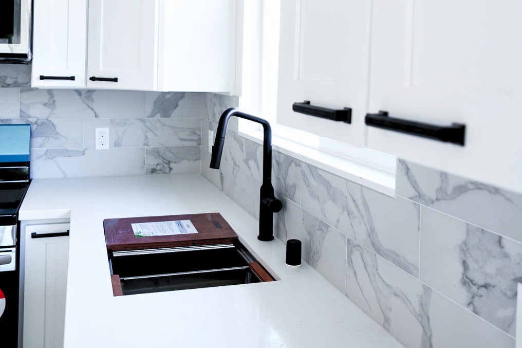 Black modern faucet and marble backsplash detailing kitchen sink area in coastal ADU.
