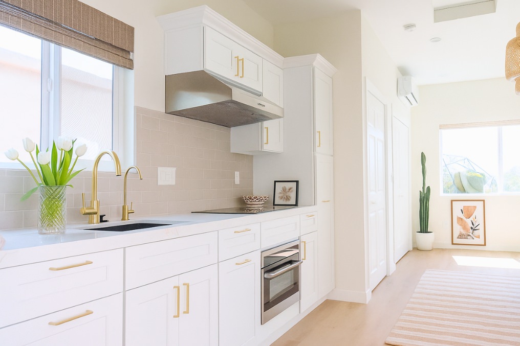 White cabinetry and gold accents highlight the sophisticated design of this modern ADU kitchen.