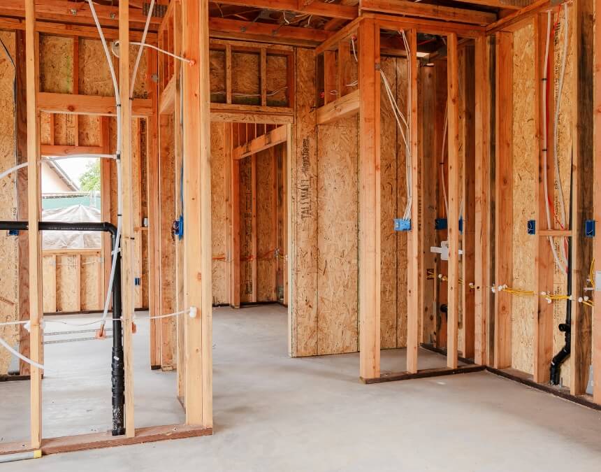 Framed interior of an ADU under construction, showing exposed wood structure and pre-installed electrical and plumbing lines.