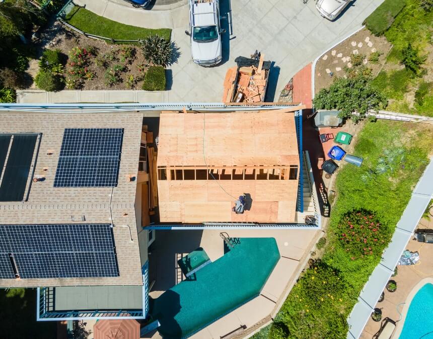 Suburban neighborhood view showing a solar-equipped home and an ADU under construction behind it.