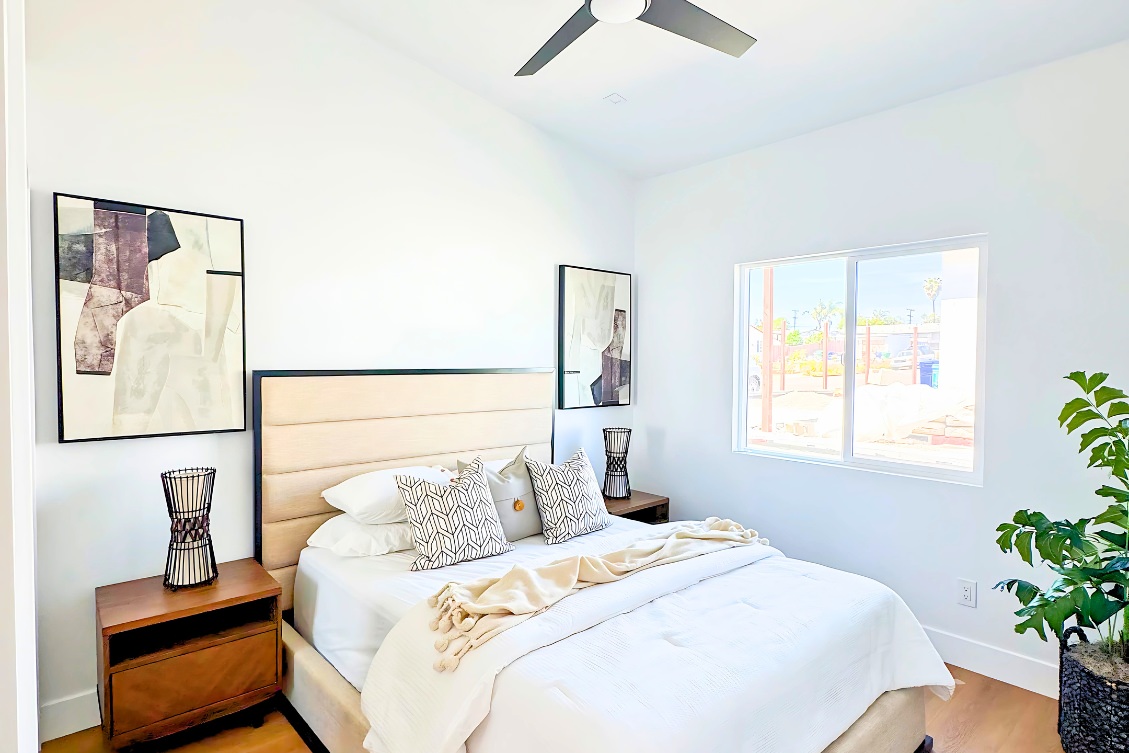 Modern ADU bedroom with black metal bedframe, wood nightstand, and abstract art