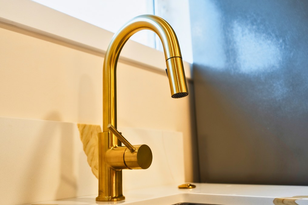 Detail of sophisticated brass kitchen faucet in modern garage conversion ADU.