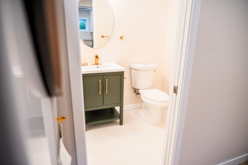 Cozy bathroom with elegant vanity and gold fixtures in ADU garage conversion.