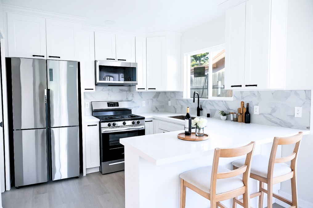 Sleek, white kitchen with stainless steel appliances and coastal-inspired finishes in ADU garage conversion.