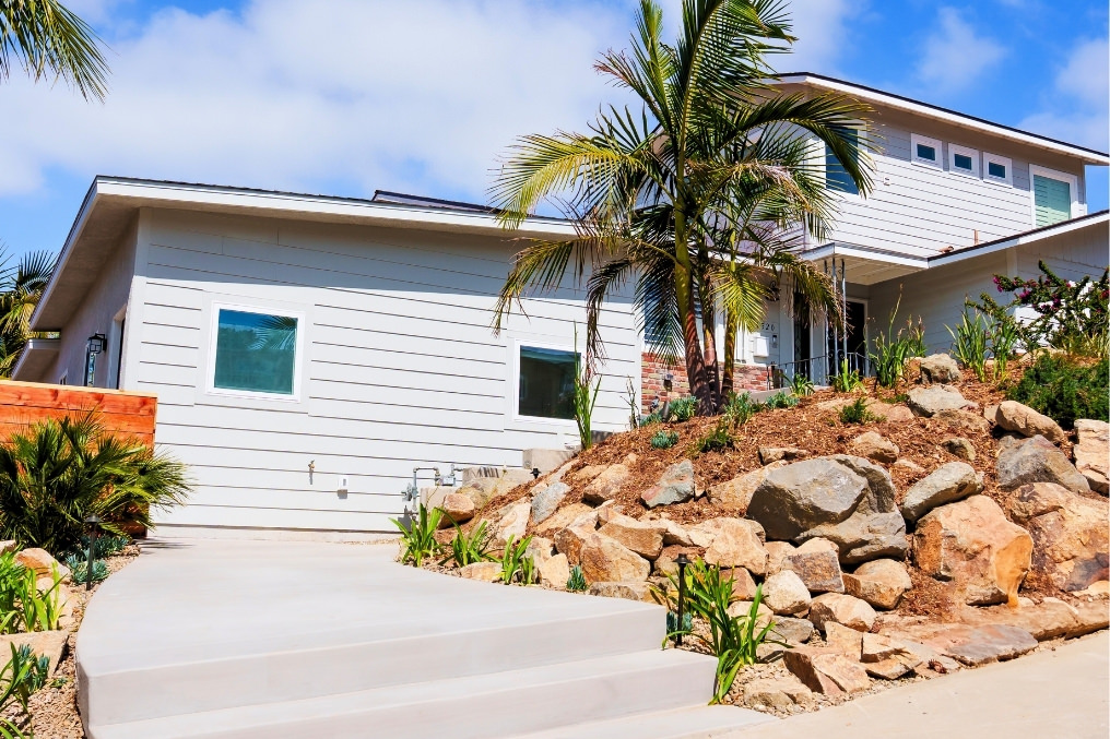 Front exterior of attached ADU showcasing modern design, stylish siding, landscaped walkway, and lush greenery.