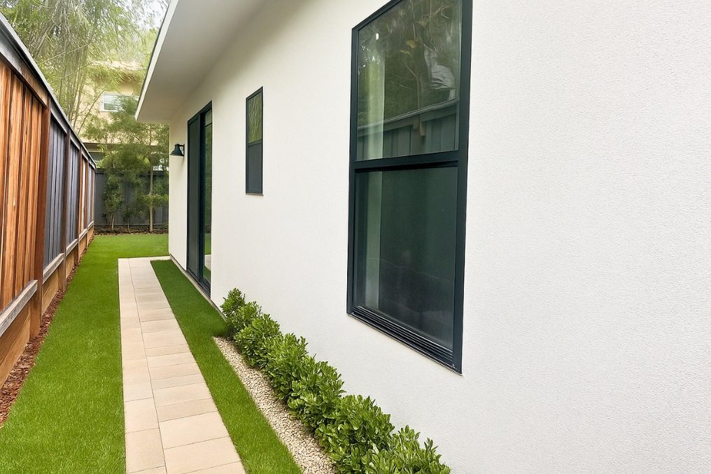 Clean and serene side pathway with neatly maintained greenery leading to contemporary ADU.