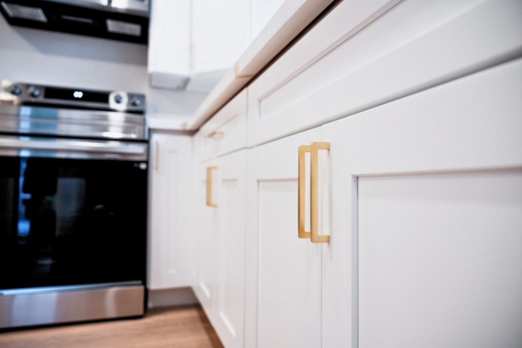 Close-up of white kitchen cabinetry featuring modern brass handles in studio ADU.