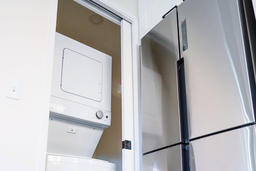 Compact laundry closet featuring stacked washer and dryer in garage conversion ADU.
