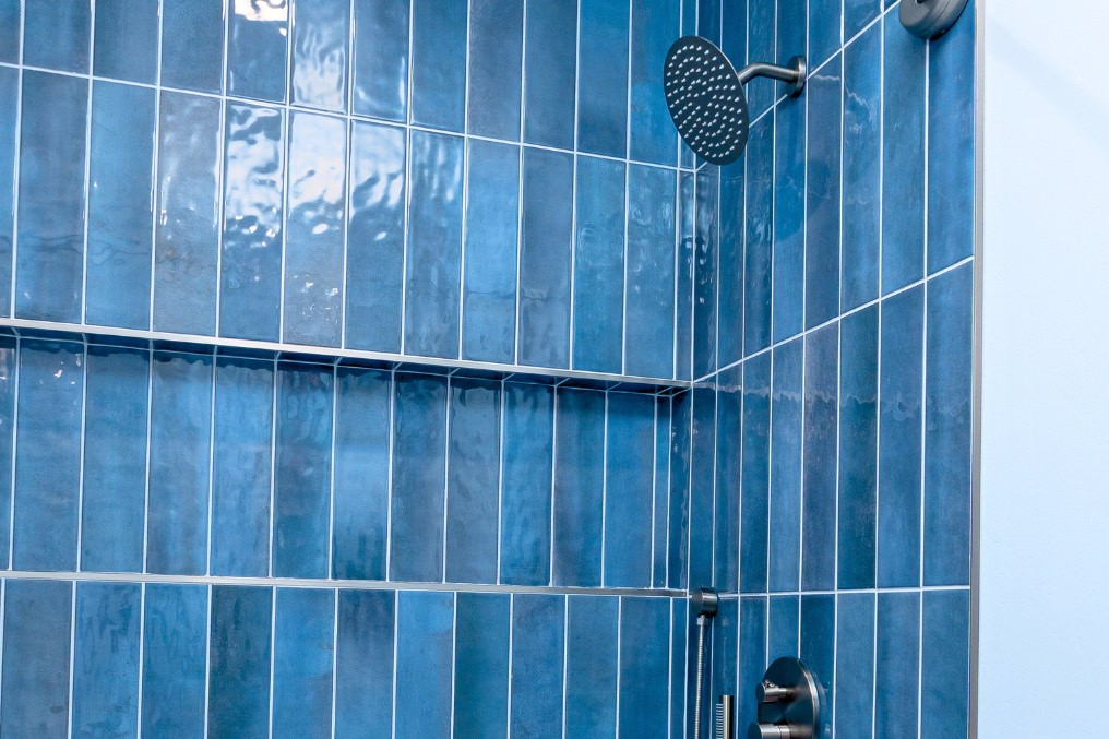 Vibrant blue vertical subway tiles in contemporary shower area with modern fixtures