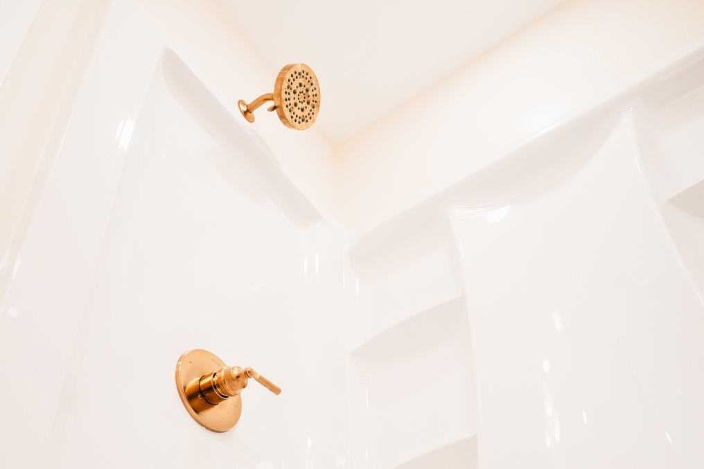 Detail of luxurious gold showerhead and faucet in modern shower of converted garage studio ADU.