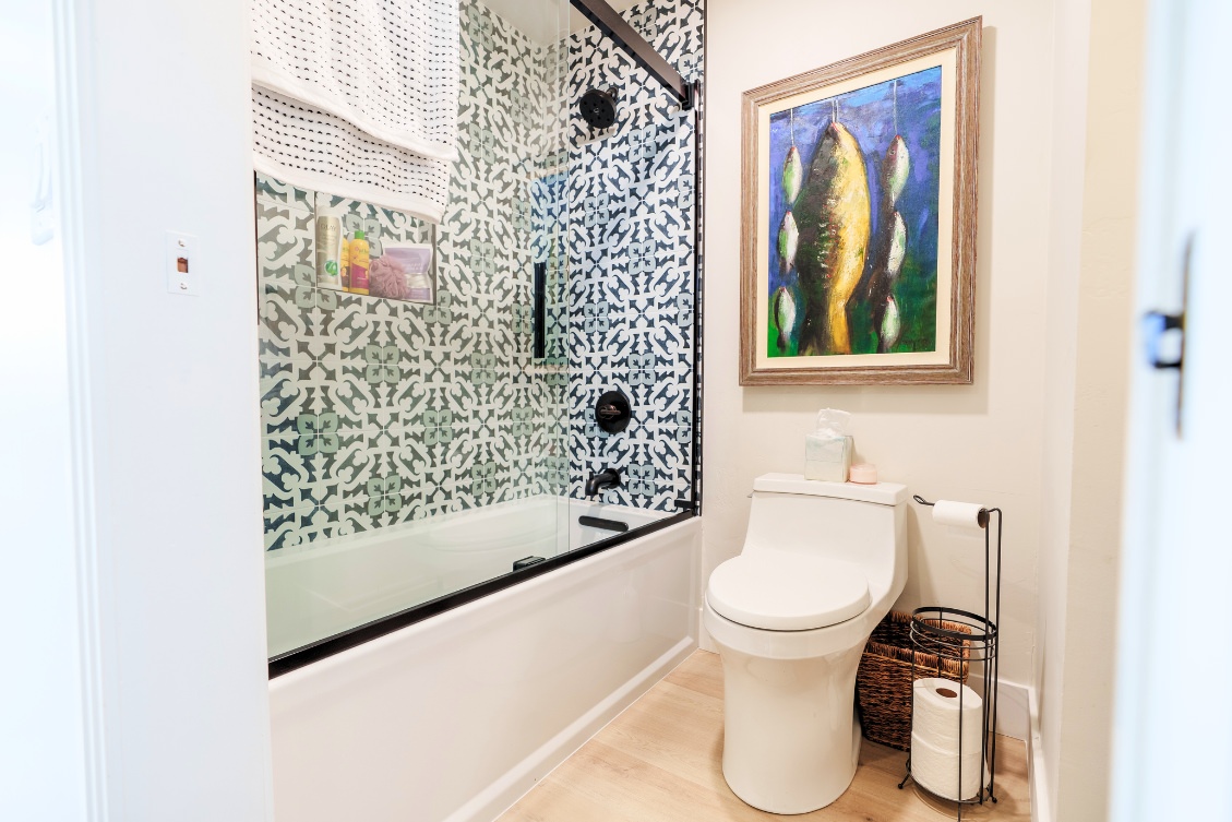 ADU bathroom with decorative tile shower wall, glass tub enclosure, and contemporary toilet