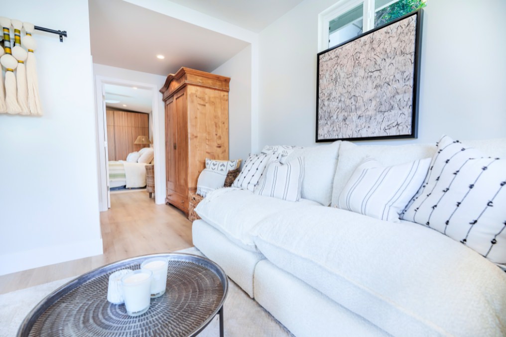 Compact ADU living area with plush sofa, wooden armoire, and wall art accents