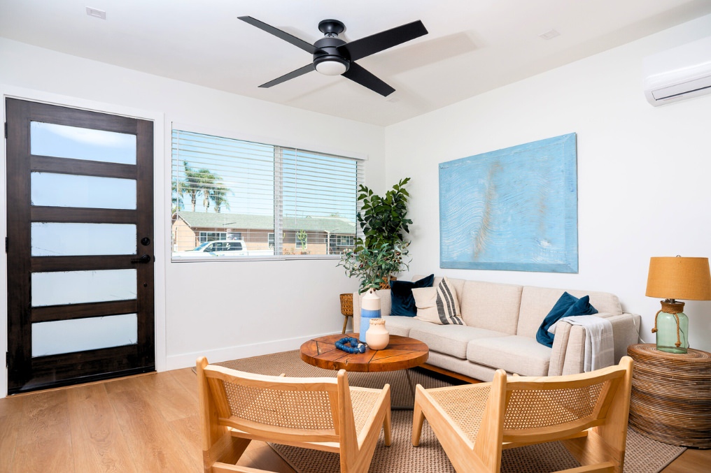 Stylish ADU living area with neutral sofa, wood accents, and ceiling fan