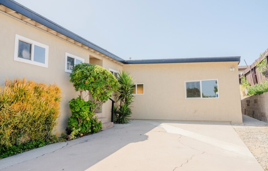 Exterior view of a completed 1200 square foot ADU with stucco finish and landscaped entryway