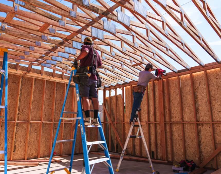“Choosing a Local San Diego ADU Builder” image of ADU framing with crews working under roof trusses.