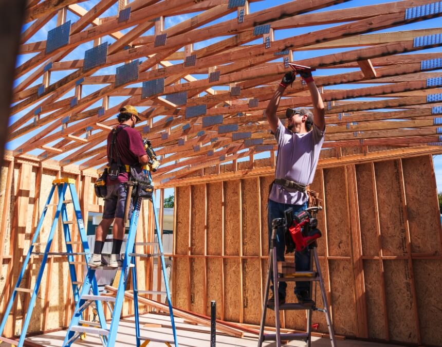 “Understanding ADU Builders” image of interior framing and roof trusses being installed by a construction crew.