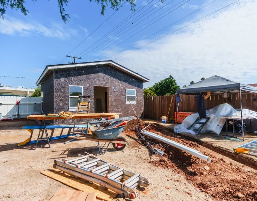 “What Is an ADU Builder” image showing a detached backyard ADU in progress, with exterior shell complete and sitework underway.