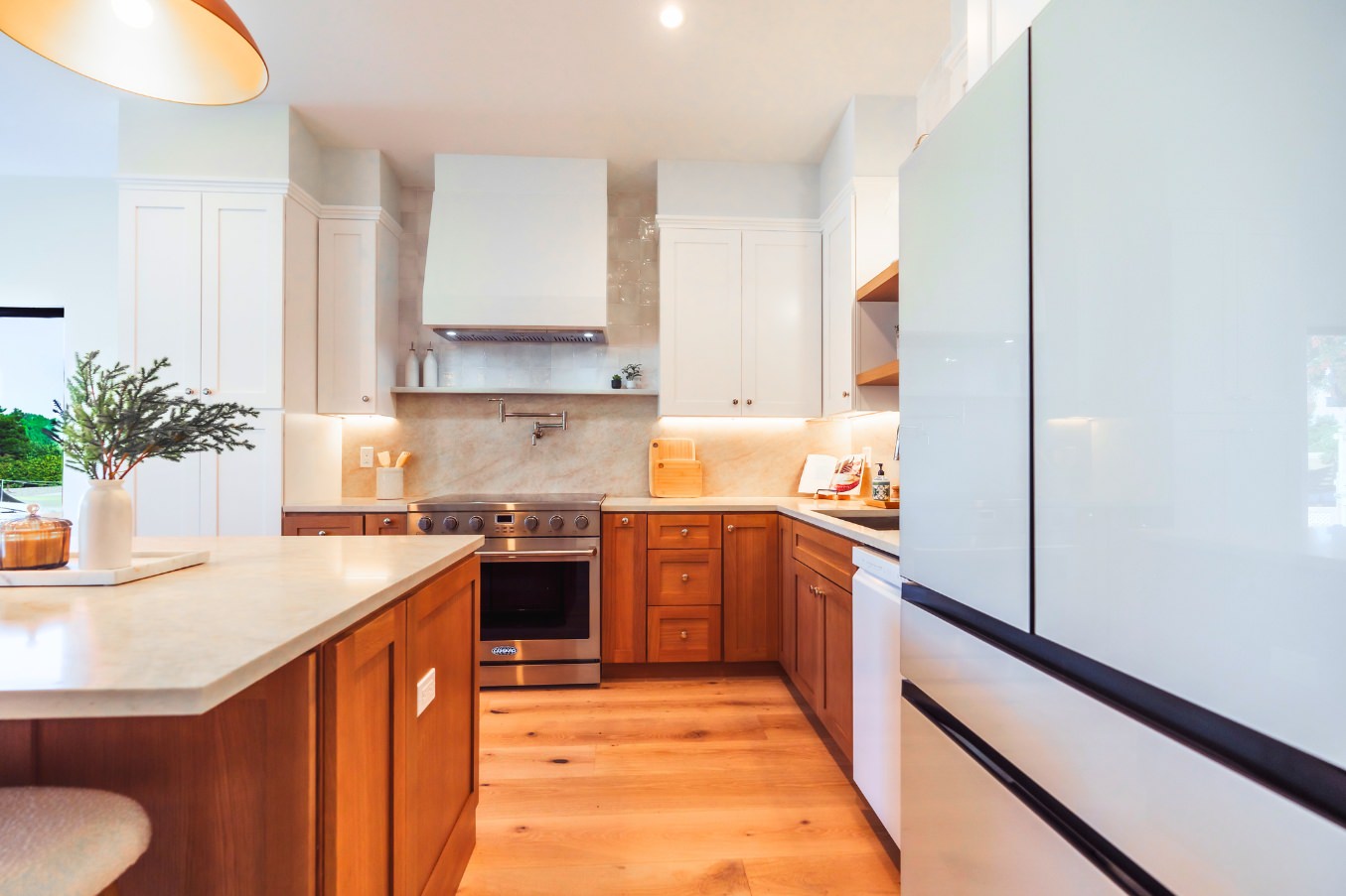 Linda Vista Detached ADU kitchen showcasing the built-in range, upper white cabinets, warm wood lower cabinets, and modern lighting.